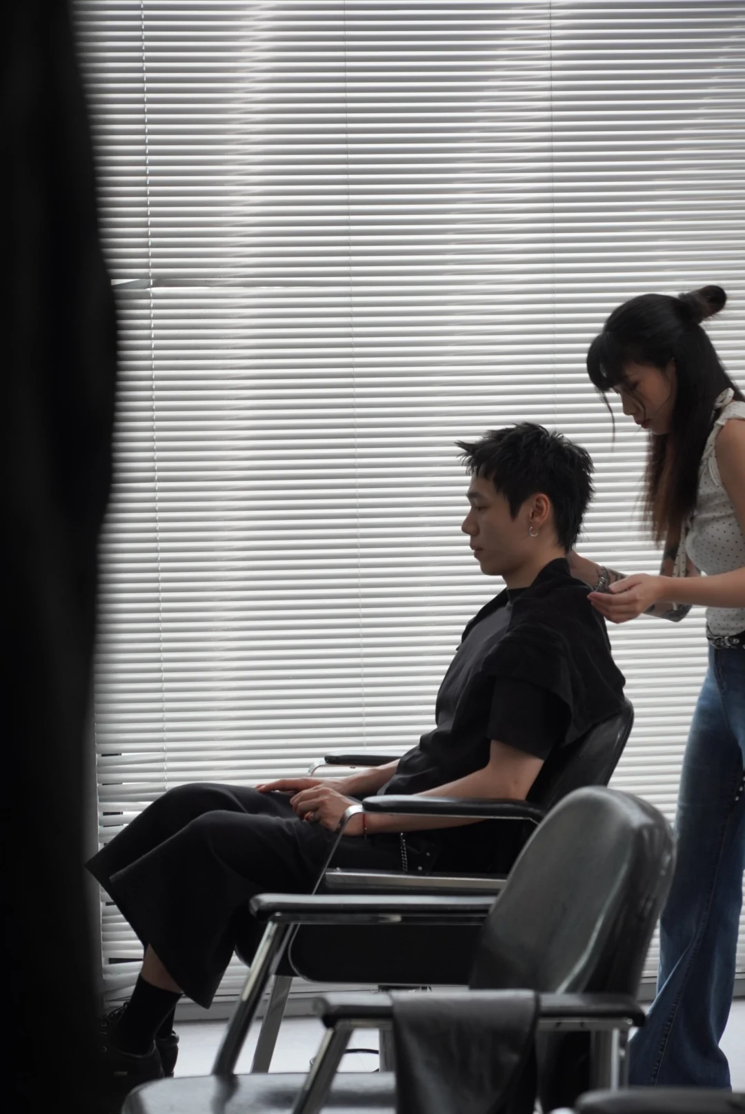 A client in a work chair with a designer attending to their hair