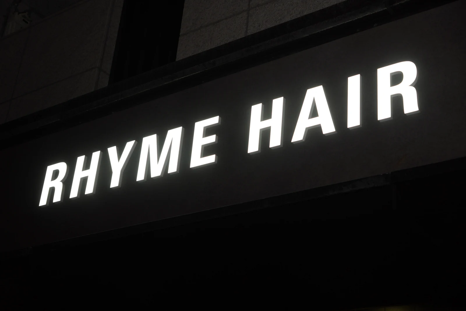 The illuminated RHYME HAIR sign